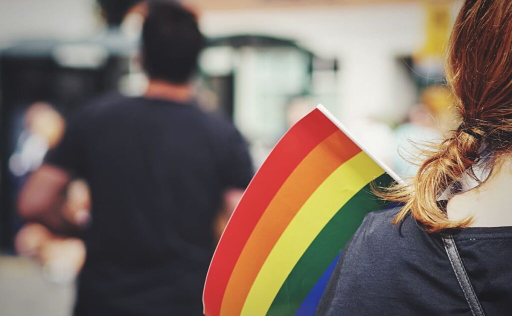 Persona sosteniendo una bandera arcoíris durante una celebración del orgullo LGTBIQ+, símbolo de diversidad e inclusión social.