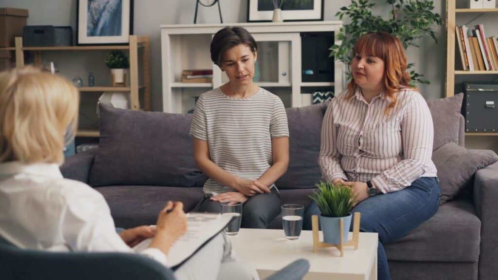 Profesional de la intervención socioeducativa realizando una sesión de orientación y terapia familiar sistémica en un despacho.